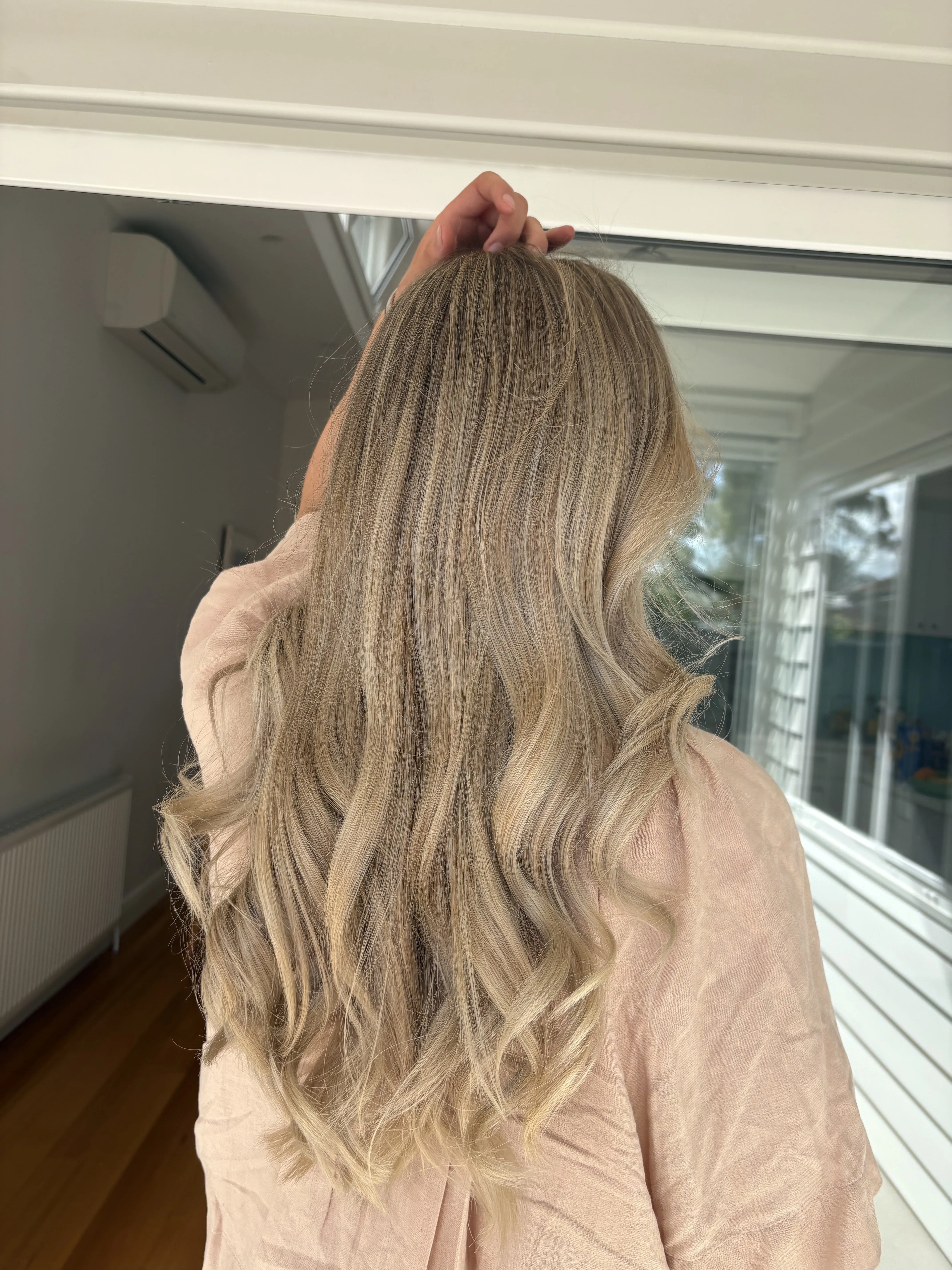 Natural blonde balayage long waves near a window