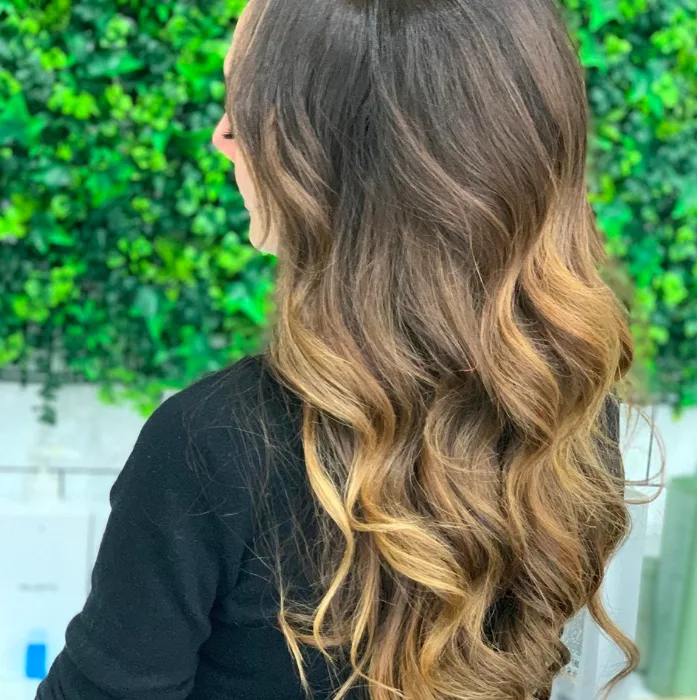 Brunette to caramel balayage waves against green ivy