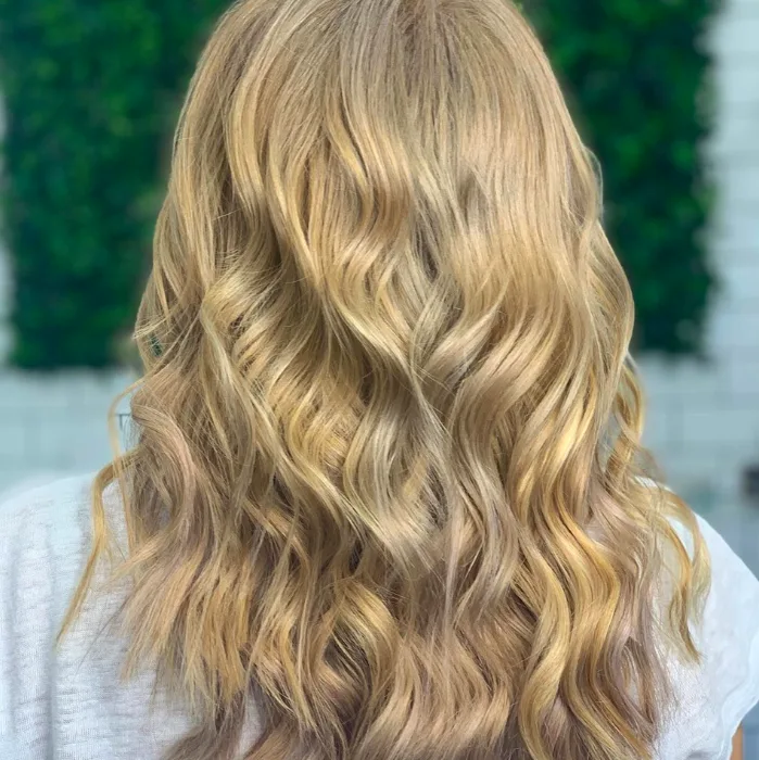 Golden blonde beach waves against green ivy